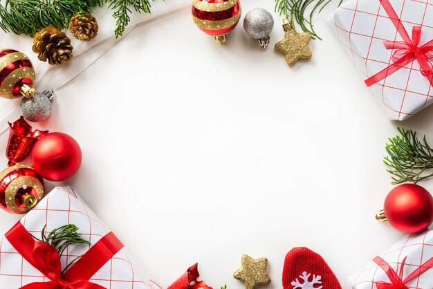 Weihnachtsgeschenkbox mit roten Ball- und Kiefernkegeln auf weißem Hintergrund.