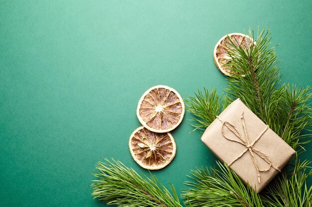 Weihnachtsgeschenkbox und Kieferniederlassungen mit Dekoration auf Draufsicht des grünen Hintergrundes