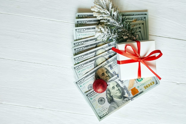 Weihnachtsgeschenkbox und US-Dollar-Scheine auf weißem Holzhintergrund