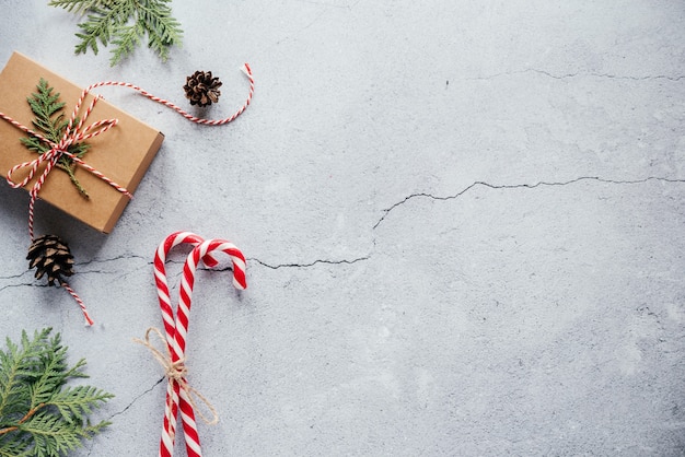 Weihnachtsgeschenkbox verziert mit einem Thujazweig und einer Grußkarte mit Zuckerstangen