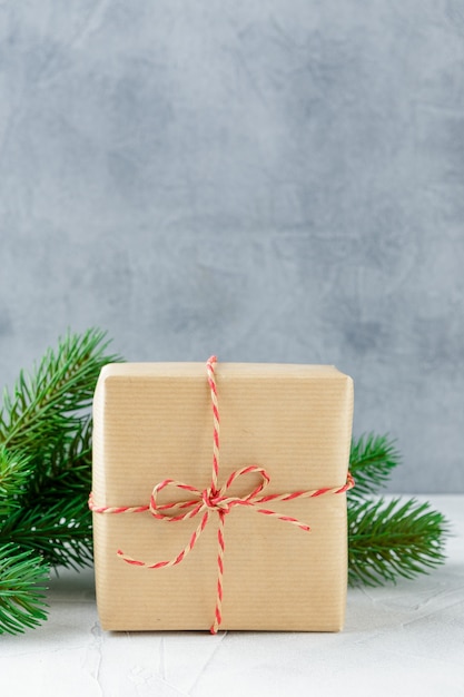 Weihnachtsgeschenkboxen aus Kraftpapier und Fichtenzweigen auf grauem Beton