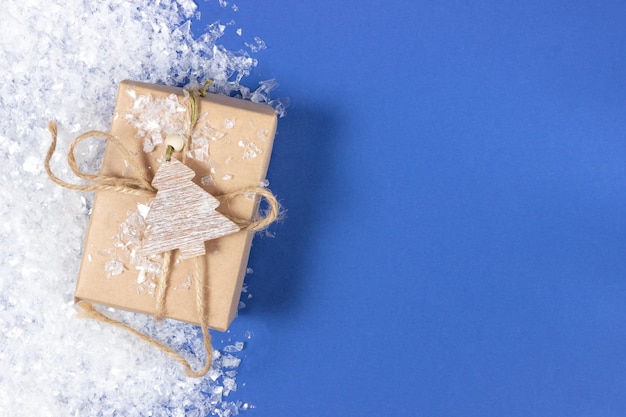 Weihnachtsgeschenkboxen eingewickelt in Kraftpapier auf blauem Hintergrund mit Weihnachtsdekorationen Urlaubs- und Weihnachtskonzept von oben