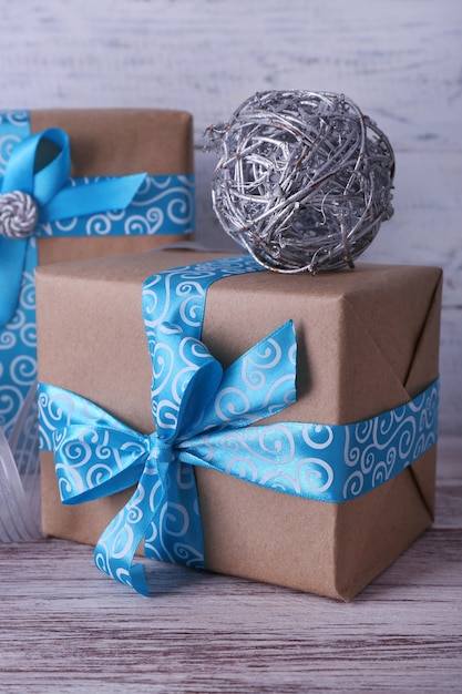 Weihnachtsgeschenkboxen mit blauem Band auf dem Tisch an der Holzwand