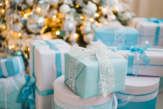 Foto weihnachtsgeschenkboxen mit blauer schleife und bokeh-lichtern auf holzoberfläche