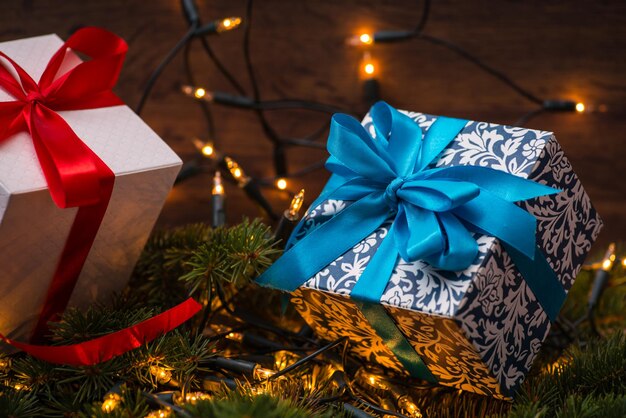 Weihnachtsgeschenkboxen mit roten und blauen Schleifen und Lichtern auf Holzoberfläche