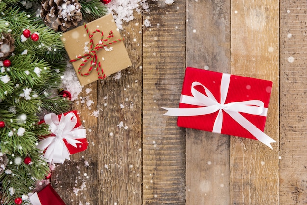 Weihnachtsgeschenkboxen mit verzierenden Einzelteilen und Schnee auf altem hölzernem Hintergrund