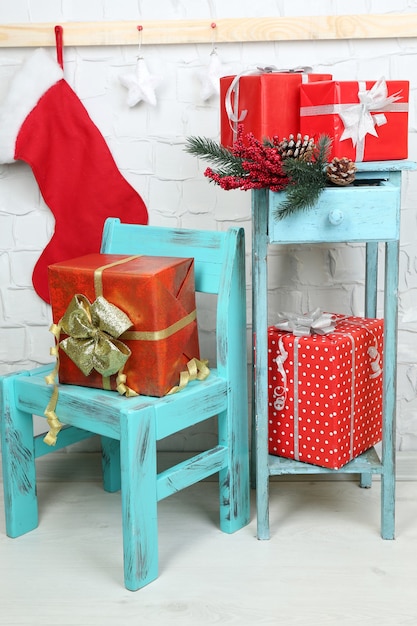 Weihnachtsgeschenke auf blauem Stuhl und Bücherregal auf Backsteinmauer