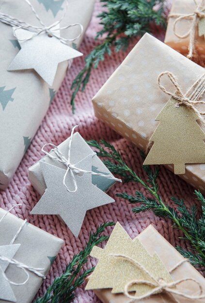 Weihnachtsgeschenke auf rosa gestricktem Textilhintergrund. Kraftpapier-Geschenkboxen, Weihnachten und Happy New Year-Zusammensetzung. Flacher Lay-Stil, Ansicht von oben