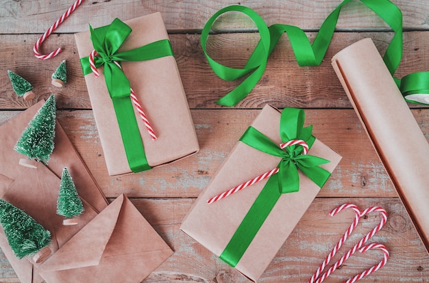 Weihnachtsgeschenke eingewickelt im Kraftpapier mit grüner Draufsichtebene des Bandes legen auf hölzernes