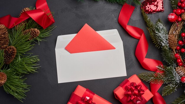 Weihnachtsgeschenke, eingewickelt in rotes Papier, und ein Brief auf schwarzem Hintergrund