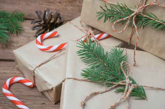Weihnachtsgeschenke oder Geschenkbox in Kraftpapier verpackt mit Dekoration und Tannenzweig auf rustikalem