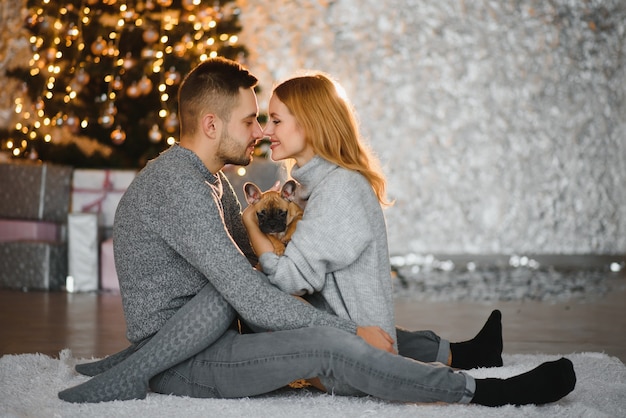 Weihnachtsgeschenke und Glück zwischen einem jungen Paar und einem niedlichen Hund