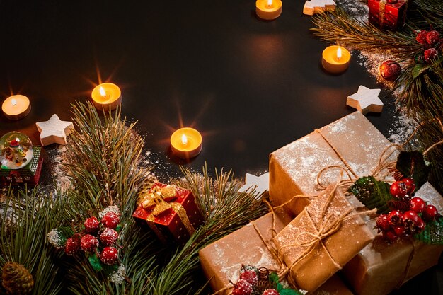 Weihnachtsgeschenke, Weihnachtsbaum, Kerzen, farbiges Dekor, Sterne, Kugeln auf schwarzem Hintergrund. Ansicht von oben. Platz kopieren. Stillleben Wohnung lag Neujahr