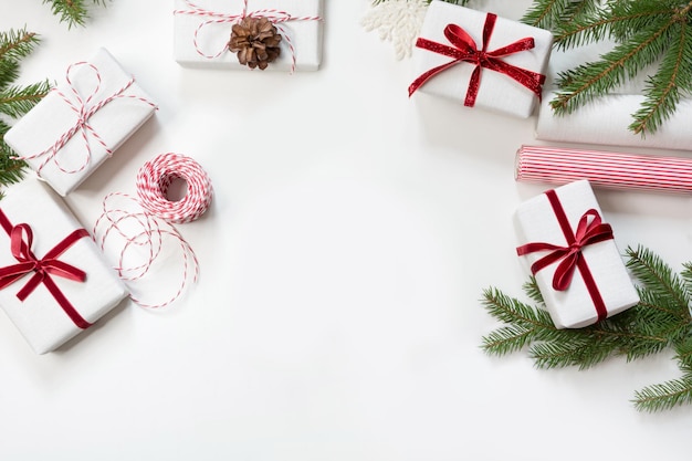 Weihnachtsgeschenkschachteln eingewickelt in weißes Bastelpapier und dekoratives rotes Seilband