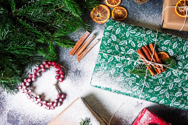 Foto weihnachtsgeschenkverpackungsfoto mit schnee neujahrskisten mit kraft rot-grünem papierdekoration zimt trockene orangen