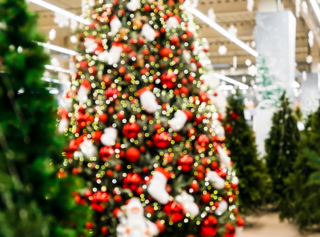 Weihnachtsgeschmückter Baum unter nicht geschmückten Tannen in einem Geschäft. Weihnachtsmarkt in einem großen Laden. Weihnachtsgrußkarte.