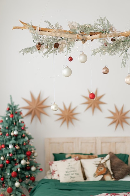 Weihnachtsgeschmücktes Schlafzimmer mit Weihnachtsbaum und grüner Bettwäsche. Bokeh-Effekt