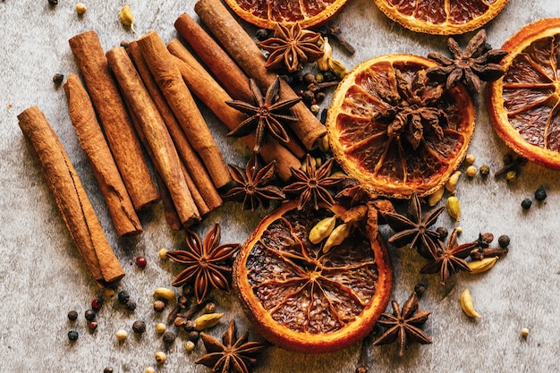 Weihnachtsgewürz. zimt, getrocknete orangen und anis auf einem grauen tisch.