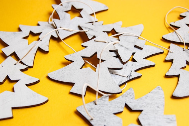 Weihnachtsgirlande in Form von Holztannen auf gelbem Hintergrund