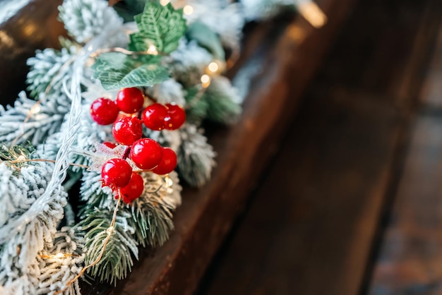 Weihnachtsgirlande mit roten Beeren und Schnee auf dem Baum am Fenster Hochwertiges Foto