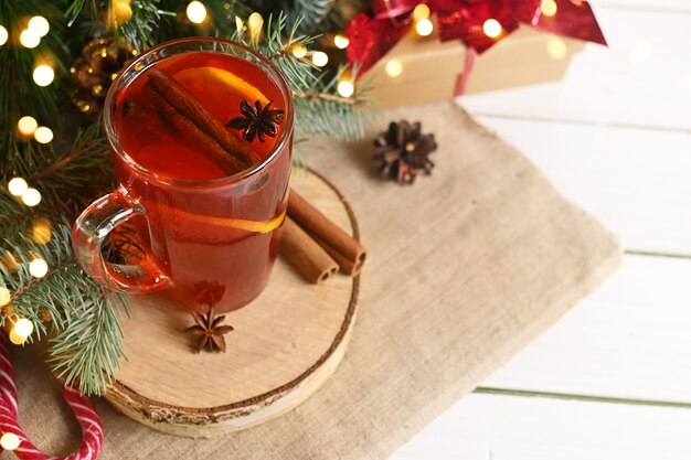 Weihnachtsglas heißer roter Glühwein mit Orangen, Nelke, Zimt und Anis in der Nähe von Geschenken und Dekoration