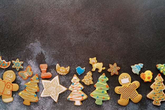 Foto weihnachtsglasierte kekse liegen entlang der unteren kante auf einem schwarzen, schäbigen hintergrund