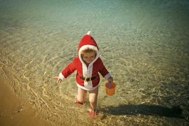 Weihnachtsglückliches kind mit eimer im wasser.