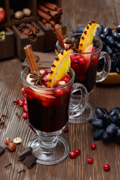 Weihnachtsglühwein mit Apfel, Cranberry, Orange, Gewürzen und Schokolade auf einem Holztisch