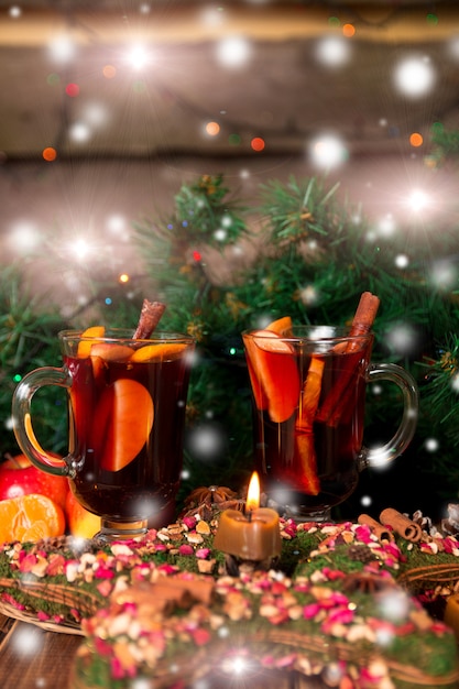 Weihnachtsglühwein mit Früchten und Gewürzen auf Holztisch.