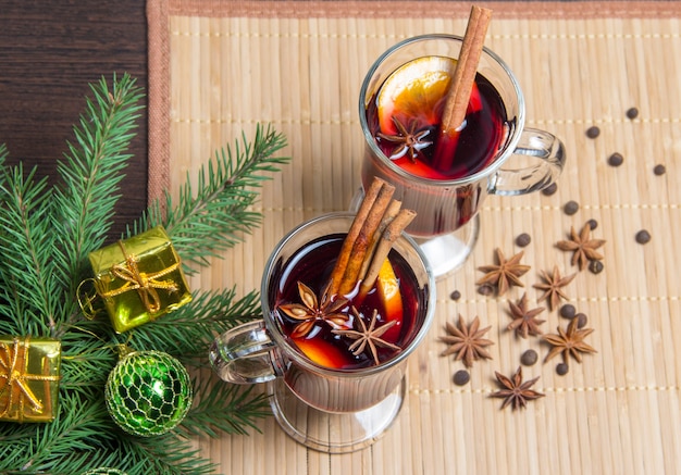 Weihnachtsglühwein mit Zimt und Orange. Auf dem Tisch liegen Fichtenzweige und Spielzeug