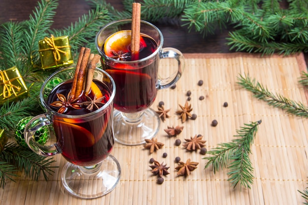 Weihnachtsglühwein mit Zimt und Orange. Auf dem Tisch liegen Fichtenzweige und Spielzeug