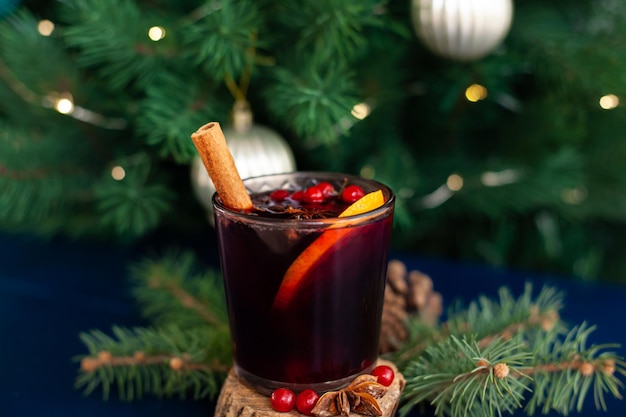 Weihnachtsglühwein mit Zimtstange, Orange, Anis und Nelken auf blauem Grund. Winterferien.