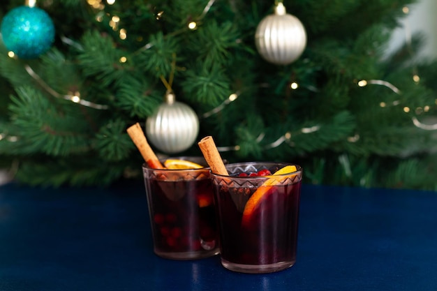 Foto weihnachtsglühwein mit zimtstange, orange, anis und nelken auf blauem grund. winterferien.