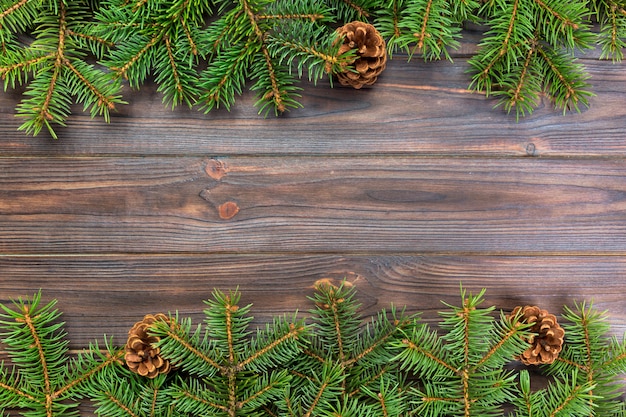 Weihnachtsgrauer hölzerner Hintergrund mit Tannenbaumrahmen und Kegel copyspace. Draufsicht leeren Raum