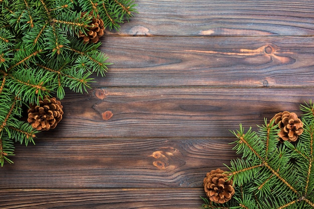 Weihnachtsgrauer hölzerner Hintergrund mit Tannenbaumrahmen und Kegel kopieren Raum.