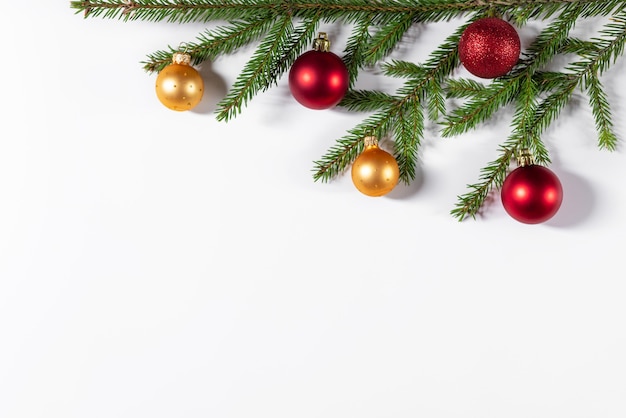 Weihnachtsgrenze aus Tannenzweigen, goldenen und roten Kugeln auf weißem Hintergrund.