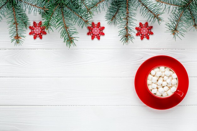 Weihnachtsgrußkarte mit roter Tasse Kaffee und Schneeflocken. Neujahrsrahmen mit festlichen Dekorationen. Fichte Zweige. Vorlage mit Kopienraum. Muster mit Platz für Text. Wintermodell.