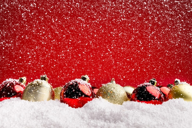 Weihnachtsgrußkartendesign und -hintergrund. Rote und silberne Kugeln im Schnee auf rotem Hintergrund, Kopierraum