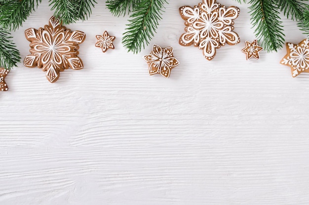 Weihnachtshausgemachte Lebkuchenplätzchen und Tannenzweige auf weißem hölzernem Hintergrund