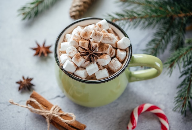 Weihnachtsheiße Schokolade mit Marshmallow, Zimt, Sternanis und Zuckerstange mit Tannenzweigen und Zapfen, gemütlicher Weihnachtshintergrund