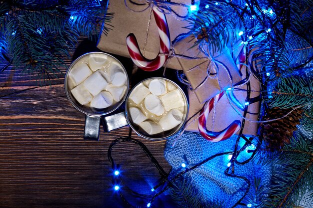 Weihnachtsheißer Kakao mit Marshmallow-Girlande und Fichtenzweigen auf einem hölzernen Hintergrund von oben