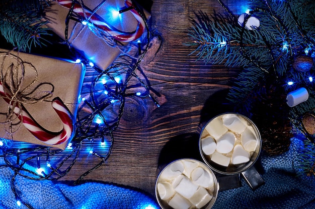 Weihnachtsheißer Kakao mit Marshmallow-Girlande und Fichtenzweigen auf einem hölzernen Hintergrund von oben