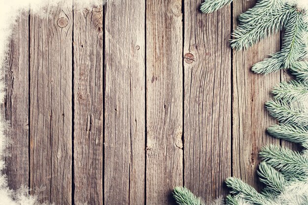 Weihnachtshintergrund aus Holz mit Tanne und Schnee Ansicht mit Kopierplatz für Ihren Text Retrotoniert