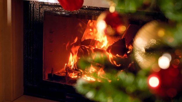 Weihnachtshintergrund des brennenden Kamins und des verzierten Weihnachtsbaums am Haus