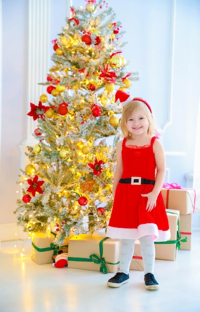 Weihnachtshintergrund Ein Mädchen in einem Kleid des Weihnachtsmanns steht in Weihnachtsdekorationen