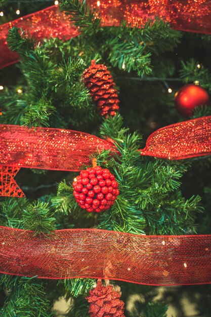 Weihnachtshintergrund eines Baumes, der mit roten glänzenden Kugeln und Dekorationen Bokeh-Lichtern verziert wird