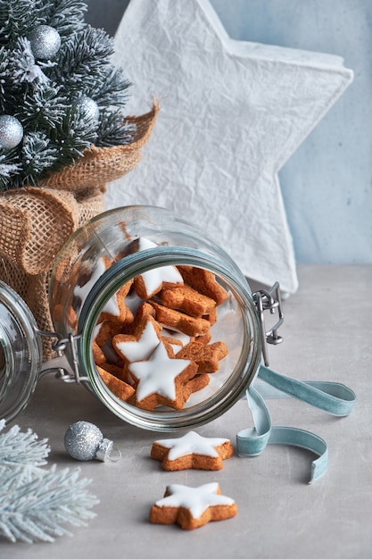 Weihnachtshintergrund in Grün und Blau mit leckeren Stern-Ingwer-Keksen in einem Glas mit verziertem Weihnachtsbaum