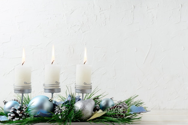 Weihnachtshintergrund mit blauen Verzierungen und brennenden Kerzen