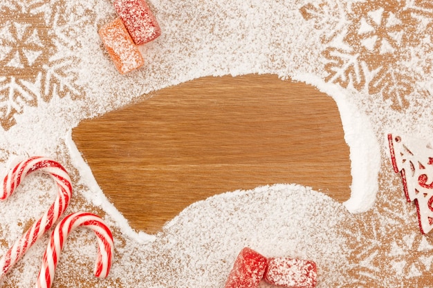 Weihnachtshintergrund mit Bonbons, Schneeflocken und dekorativem Weihnachtsbaum auf Holztisch