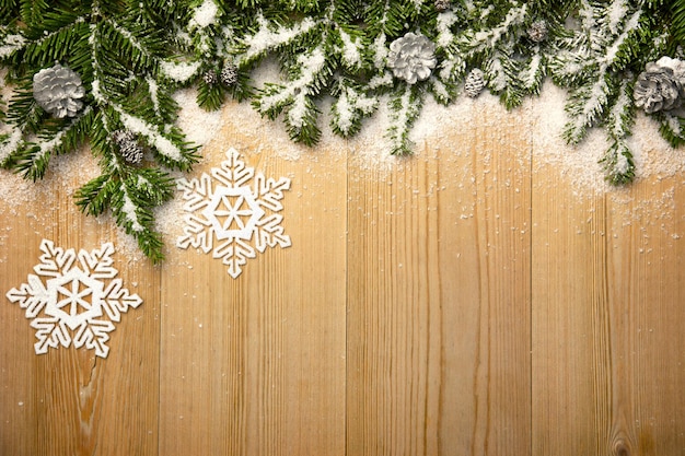 Weihnachtshintergrund mit dekorativen Schneeseen und Kegeln auf Holz mit Schnee